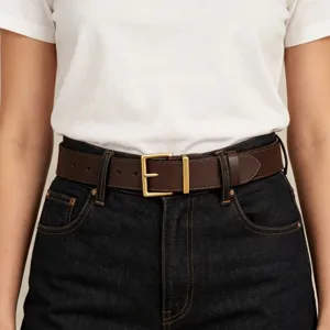Close-up detail of classic brown leather belt with square gold buckle on dark denim.