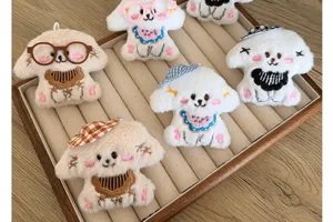 Collection of cute plush dog charms with glasses and hats in a display tray