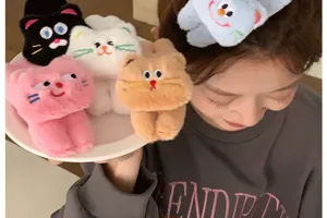 Detail view of colorful plush cat hair clips on a white plate and worn by an Asian model.