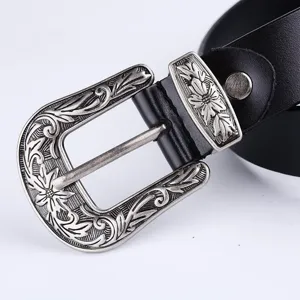 Close-up of vintage carved metal belt buckle with intricate floral texture, retro style.