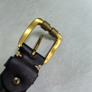 Close-up detail of vintage distressed zinc alloy men's roller belt buckle and leather strap.