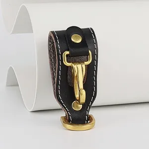 Close-up detail of black genuine leather belt key holder with brass metal hook and D-ring.