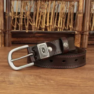 Close-up of the vintage brown leather belt with carved metal buckle and fine stitching details.