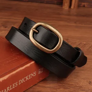 Close-up detail of a black genuine leather women belt with retro brass oval metal buckle.