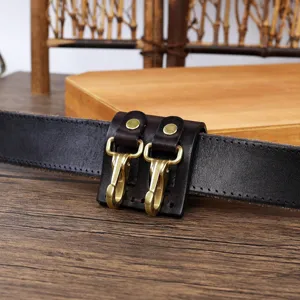 Leather belt key holder detail shot showing brass hooks and rivets on dark brown leather loop.