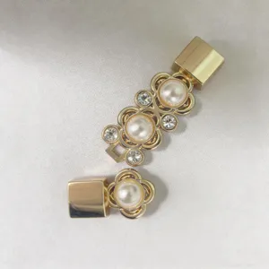 Vista dettagliata della fibbia per cintura dorata con fiore di perla e strass scintillanti.
