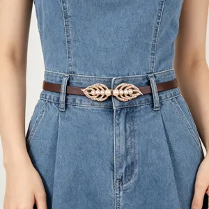 Λεπτομερής όψη λεπτής καφέ δερμάτινης γυναικείας ζώνης με χρυσή αγκράφα φύλλου και πέρσας.