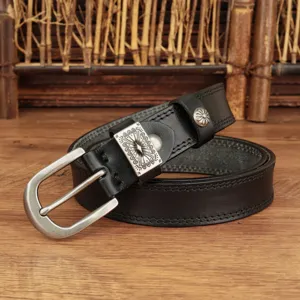 Close-up detail of a vintage black leather belt featuring an intricate engraved metal buckle.