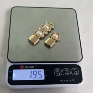 Dettaglio fibbia per cintura in metallo dorato con design floreale perla strass e peso 19.5g
