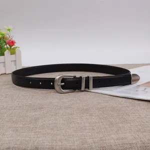 Close-up detail of a minimalist black women leather belt with vintage silver buckle and metal tip.