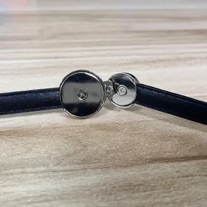 Detailed macro shot of a sleek silver asymmetric metal buckle on a thin black leather belt.