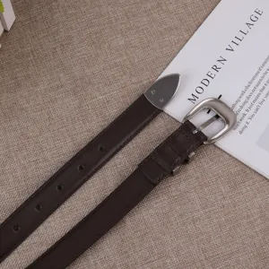 Women brown leather belt detail view with metal horseshoe buckle and tip, stylish jeans accessory.