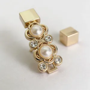 Dettaglio di fibbia per cintura dorata decorata con perle eleganti e strass luminosi.