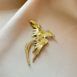 Detailed view of the gold phoenix brooch back, showing secure pin clasp and textured metal.