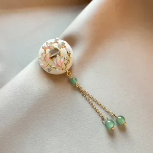 Close-up detail view of Chinese style magnolia flower brooch with jade beads tassel.