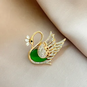 Elegant golden swan brooch featuring a green center stone and sparkling crystal rhinestones for women.