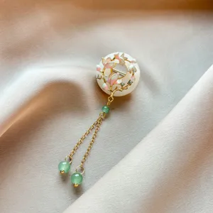 Exquisite detail of the Chinese style magnolia brooch featuring delicate jade ring and tassels.