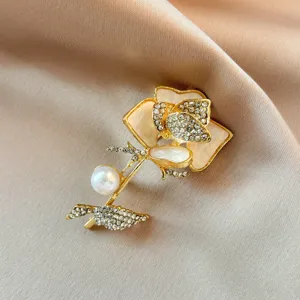 Elegant rose flower brooch detail shot featuring sparkling rhinestones and pearl embellishment.