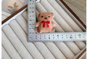 Détail macro d'un accessoire ours en peluche avec règle indiquant la taille pour le bricolage