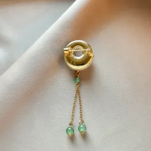 Close-up detail of traditional Chinese style gold-plated brooch with elegant hanging green jade beads.