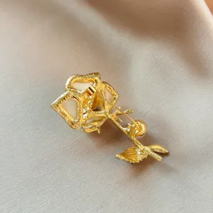 Gold rose brooch detail showing secure pin clasp and intricate leaf texture back.