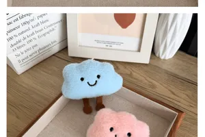 Détail de mignonnes broches en peluche en forme de nuage bleu et rose avec des sourires adorables.