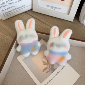 Paar schattige witte pluche konijnenpoppen met kleurrijke outfits en worteldetails