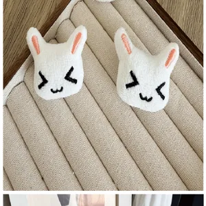 Macro view of cute white plush rabbit head DIY accessories with embroidered faces