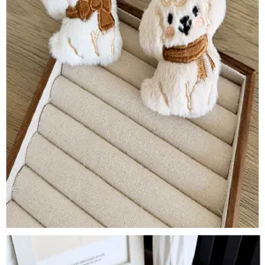Detail van schattige pluchen hondenbedels met sjaals op een beige sieradenplateau.