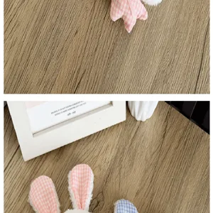 Détail d'un porte-clés lapin en peluche douce avec des oreilles à carreaux roses.