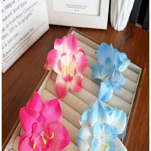 Vue détaillée de pinces à cheveux en tissu orchidée colorées sur un plateau à bijoux.
