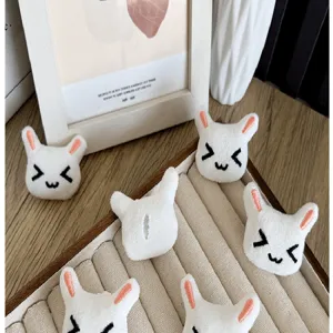Macro detail view of cute white plush rabbit head accessories with sweet embroidered faces