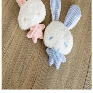 Gros plan de porte-clés lapin blancs avec corps d'étoile à carreaux roses et bleus.