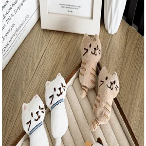 Close-up of cute white and tan plush cat brooches with detailed embroidered faces