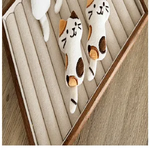 Close-up view of cute Japanese style calico cat plush brooches on a beige display tray.