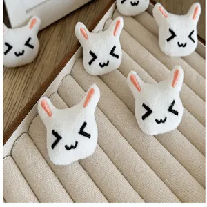 Detailed view of cute white plush rabbit head accessories on a beige display tray.