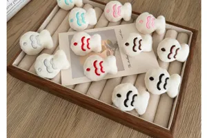 Collection of adorable white plush cartoon fish accessories with colorful embroidery on tray