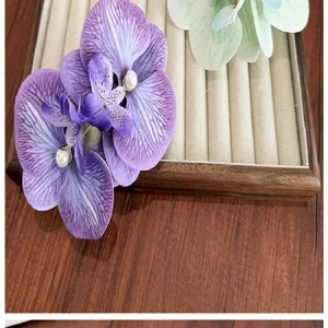 Detailed view of a large purple simulated orchid hair clip with pearl on wood tray