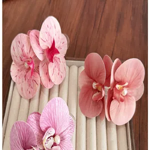 Detailed view of large realistic pink orchid hair clips with white pearls on a velvet tray
