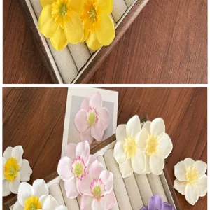 Gros plan de barrettes à fleurs de narcisse colorées dans un plateau à bijoux en bois.