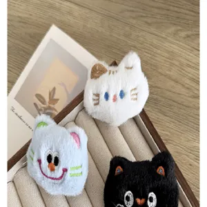 Vue détaillée de mignonnes broches chat en peluche avec fourrure et visages brodés