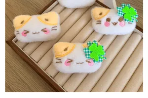 Gros plan sur d'adorables broches de chat en peluche avec visages brodés et trèfles