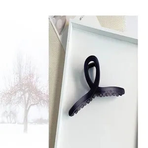 Vue détaillée d'une grande pince à cheveux mate violet foncé dans un plateau blanc