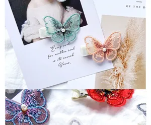 Close-up of embroidered butterfly hair clips with pearl detail on aesthetic background