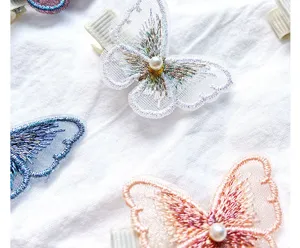 Close-up detail of embroidered butterfly hair clip featuring a lustrous pearl center