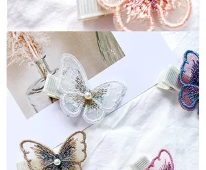 Close-up detail of elegant embroidered butterfly hair clips with pearl accents