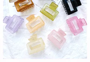 Top-down view of various colorful geometric hair claw clips on white fabric.