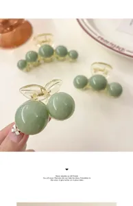 Close-up detail of glossy sage green hair claw clip with minimalist pearl-shaped design