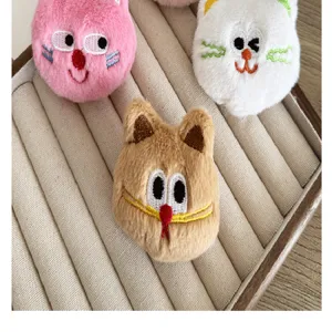 Gros plan de trois jolies broches en peluche chat en rose, blanc et brun sur plateau