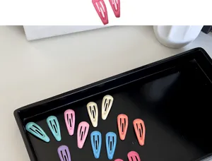 Detailed view of colorful mini BB hair clips for babies and pets in a black tray.
